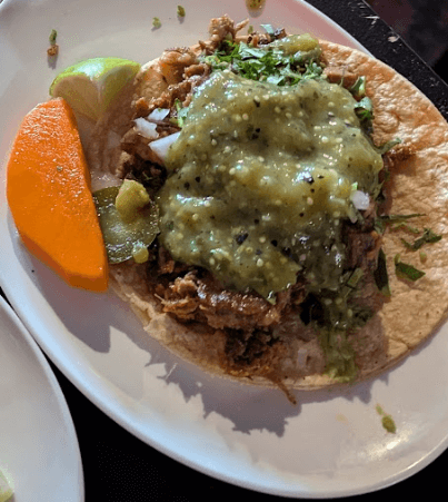 Campechano taco from Torta Boyz featuring beef brisket, green salsa, onions, cilantro, and lime wedge on a corn tortilla