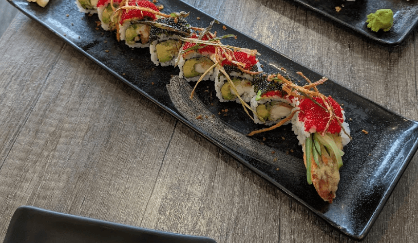 A beautifully plated Rock’n Roll sushi featuring lobster, avocado, fish roe, and crispy garnish on a sleek black rectangular dish at Sushi-ro.